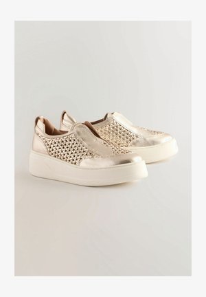 Le scarpe slip-on metalliche d'oro presentano una texture intrecciata sulla parte superiore, una finitura liscia e una suola piatta bianca, offrendo un design moderno.