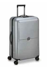 Valigia rigida argentata con forma rettangolare, zip nera, manico di trasporto superiore e quattro ruote nere con bordi gialli.