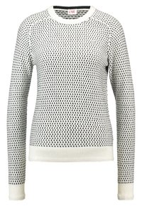 Vit tröja med svart prickig mönster, rund halsringning, långa ärmar och ribbade muddar. Materialet verkar mjukt och strukturerat.