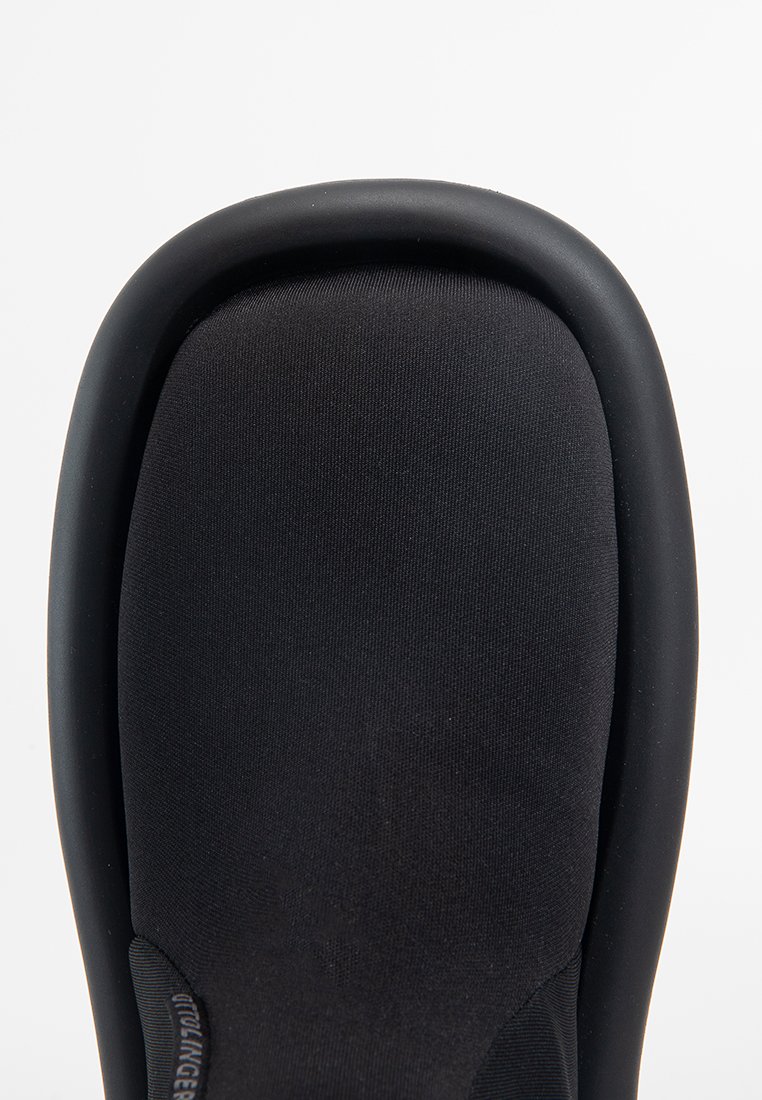 Czarne wsuwane buty z gładkim, zaokrąglonym noskiem i elastyczną, teksturowaną cholewką z materiału. Wykończone matową czarną podeszwą gumową.