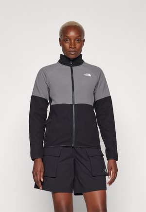Chaqueta de forro polar con un panel superior gris y una sección inferior negra. Cuello alto, cremallera completa y bolsillos laterales. Se lleva con pantalones cortos cargo negros.