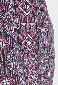Tissu à motif avec des formes géométriques en rose, violet et blanc sur fond sombre, avec une texture lisse et extensible.