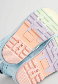 Suela de zapatillas azul claro con un patrón de degradado en rosa pastel, púrpura y verde. Goma texturizada para mayor tracción, con un diseño geométrico.