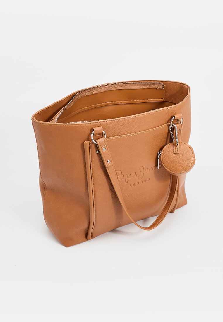 Bolso tote de piel marrón con un acabado texturizado, cuenta con asas dobles, cierre de cremallera y un charm circular removible. Logo grabado en la parte frontal.