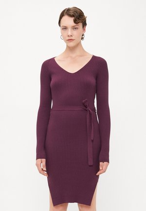Robe en maille de couleur violet profond, avec un col en V, des manches longues, une texture côtelée, et une ceinture à nouer accentuant la taille, finissant au milieu de la cuisse.