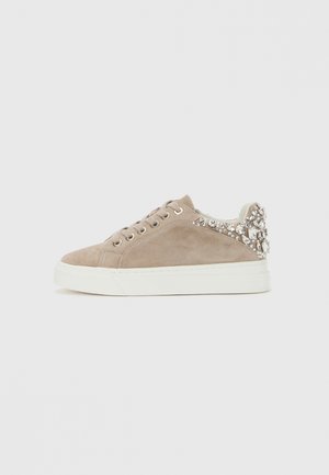 Sneaker in suede beige con suola bianca, parte anteriore con lacci e decorazione di gioielli trasparenti e argentati nell'area del tallone.