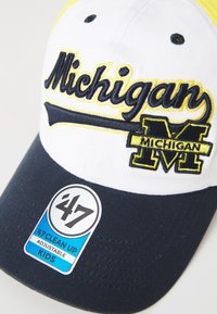 Căciulă de baseball albă și bleumarin cu "Michigan" brodată în galben și bleumarin. Are vizieră curbă și curea ajustabilă. Eticheta afișează marca și mărimea.