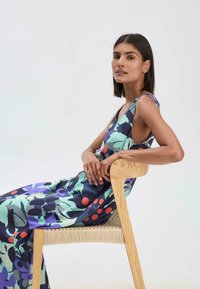 Lebhaftes ärmelloses Kleid mit einem auffälligen abstrakten Muster in grünen, blauen und roten Farbtönen; weicher Stoff mit fließender Passform.