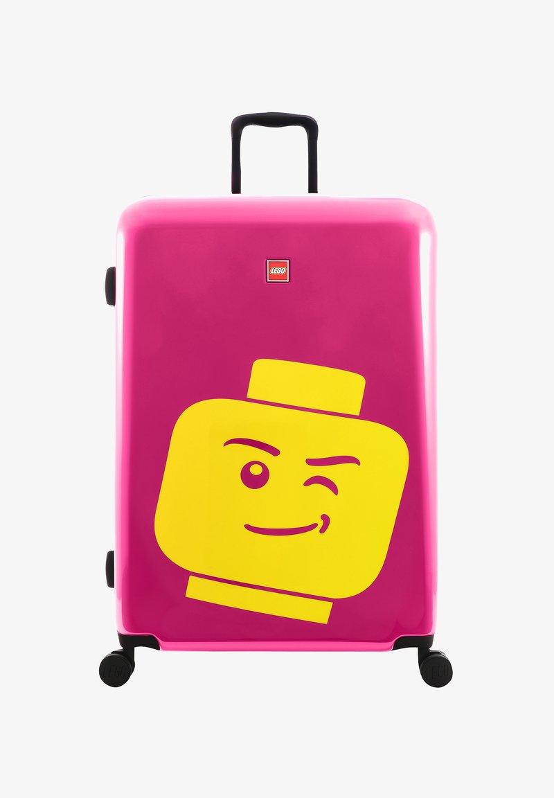 Tvrdý kufr v jasně růžové barvě s velkým žlutým designem obličeje LEGO postavičky. Má černou teleskopickou rukojeť a kola.