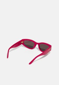 Ochelari de soare din plastic roz, cu un design elegant, rame curbate, lentile întunecate și branding auriu "vogue" pe braț.
