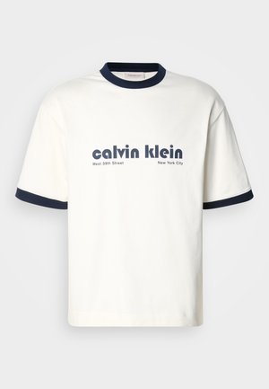 White cotton T-shirt with navy blue ribbed collar and sleeves. Features bold black text: "calvin klein West 39th Street New York City."