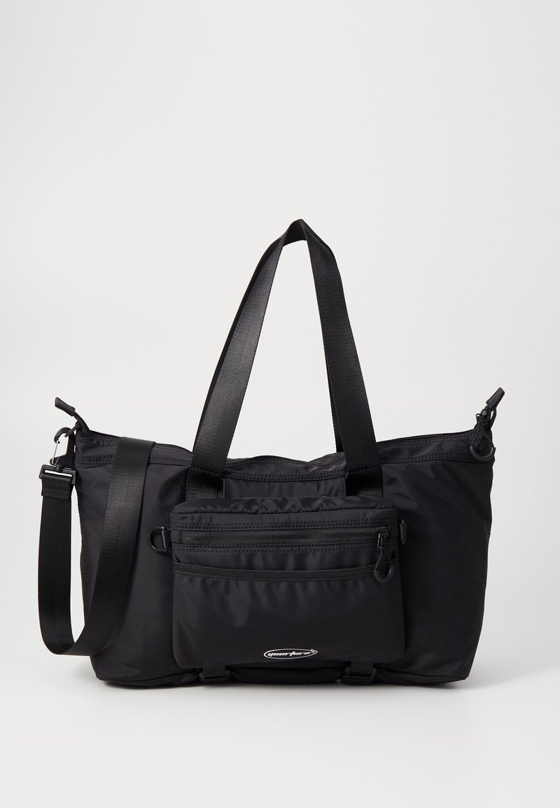 Sac fourre-tout en nylon noir avec deux poignées supérieures, bandoulière réglable et poche avant zippée avec logo.