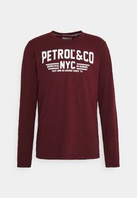 Langärmliges, burgunderfarbenes T-Shirt aus weichem Stoff mit großem, weißem Text: "PETROL & CO NYC" und zusätzlichem, kleinerem Text darunter.