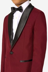 Burgundy blazer with black satin lapels, single button closure, and black pocket accents. Styled with a white shirt and black bow tie.