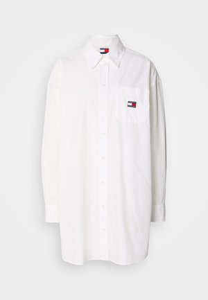 White long-sleeve button-up shirt in cotton fabric, featuring a chest pocket with a multicolored logo patch. Straight cut and classic collar.