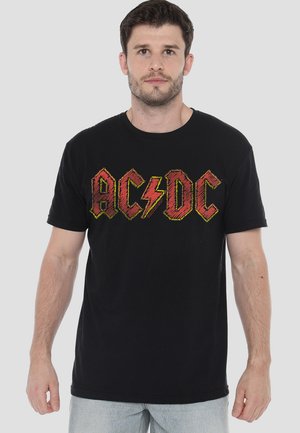 Black cotton t-shirt featuring a bold red and yellow "AC/DC" graphic design with a lightning bolt, short sleeves, and a classic crew neck.