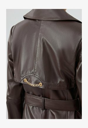 Cappotto trench in pelle marrone con un ampio colletto, vita in vita, e un accento in catena dorata sul retro dello yoke. Texture liscia, vestibilità su misura.