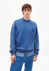 Blaues Sweatshirt aus weichem Stoff, mit rundem Kragen, gerippten B�ündchen und einem dezenten Akzentdesign auf der Brust. Kombiniert mit hellblauen Jeans.