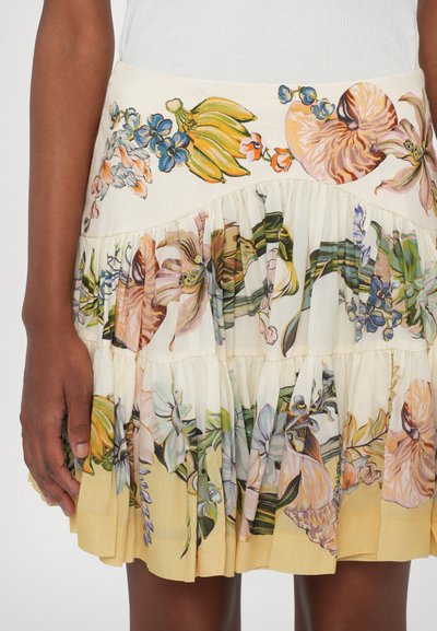 Floral-patterned skirt in light cream with ruffled tiers, featuring colorful botanical illustrations, and a pleated texture at the hem.