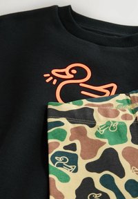 Sort sweatshirt med orange ande-grafik på brystet; parret med tan camouflage shorts med små andesilhuetter i grøn og brun.