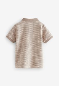 Camisa polo de tejido beige con un patrón texturizado, manga corta y un cuello acanalado en un marrón claro complementario.