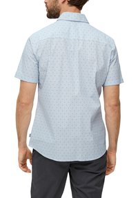 Korte mouwen shirt in lichtblauwe stof met een patroon van kleine zwarte vormen, voorzien van een klassieke kraag en een rechte snit aan de onderkant.