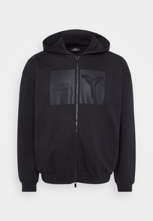 Black zip-up hoodie featuring a textured graphic patch, ribbed cuffs and hem, and a drawstring hood for adjustable fit.