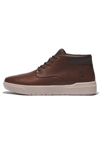 Brun läderankelboot med en slät yta, beige gummisula, rund tå och tvåfärgad design. Har metallöglor och logodetalj.