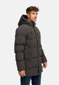 Giacca a vento grigia scura, con cappuccio, multiple tasche, texture trapuntata e zip frontale. Realizzata in materiale sintetico.