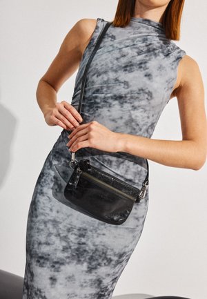 Black leather crossbody bag with a textured finish, zippered pocket, and adjustable strap, shown alongside a gray marble-patterned dress.