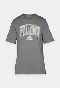 Grå bomulls t-skjorte med en iøynefallende, flerfarget "ADIDAS"-logo over brystet, med rund hals og korte ermer.