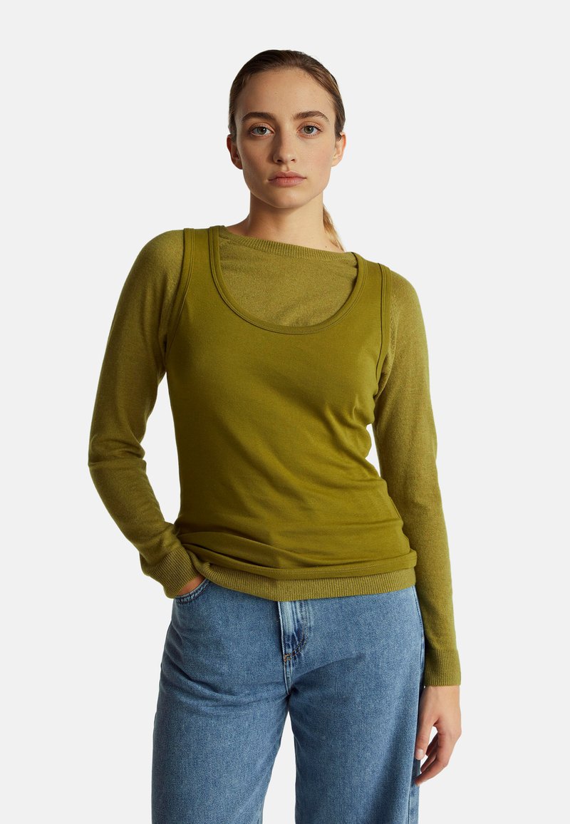 Top de manga larga verde oliva con diseño en capas; tejido suave y texturizado. Combinado con jeans de talle alto azul claro. Escote simple.