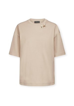 Beige T-shirt met korte mouwen van zachte stof, met een bloemenbroche accent op de linkerschouder en een ronde halslijn.