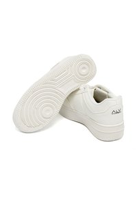 Sneaker bianche con tomaia in pelle liscia, suola in gomma con motivi circolari testurizzati e un logo discreto sul tallone.