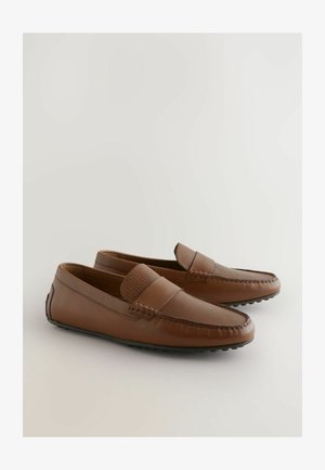 Smeđi kožni mokasini s teksturiranim platnenim remenom, zaobljenim vrhom i gumenenim potplatom. Imaju šavove duž rubova i glatku završnu obradu.