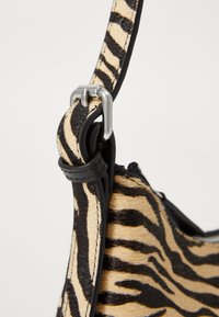 Zebra print handbag featuring a textured animal-print material, black leather accents, and a silver hardware attachment.