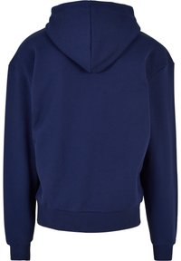 Mørkeblå hettegenser med en myk tekstur, ribbede mansjetter og nederkant. Har et enkelt, uprydet design uten mønstre eller dekorasjoner.