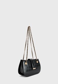 Schwarze Lederhandtasche mit Krokodilmuster, goldene Kettenriemen, die mit schwarzem Leder gewoben sind, und Vorderklappenschloss auf grauem Hintergrund.