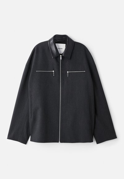 Dark gray jacket with a leather collar, front zipper, and two zippered chest pockets. Made of a textured fabric with a relaxed fit.