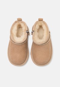 Tan suede ankle boots with soft fur lining, textured upper, and rope accent around the collar. Secured with silver hardware zippers.