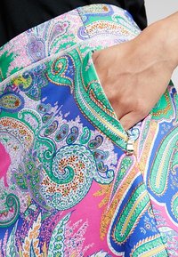 Colorful paisley-patterned fabric, featuring shades of pink, blue, and green. Includes a zip pocket and smooth texture.