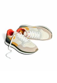 Zapatillas blancas y beige con acentos en naranja y amarillo, que cuentan con un superior de ante y cuero, cierre de cordones y una suela de goma negra.