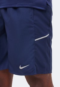 Αθλητική βερμούδα σε ναυτικό μπλε με διατρητή πλευρική επένδυση, ελαφρύ ανακλαστικό περίγραμμα και λευκό λογότυπο Nike Swoosh στο αριστερό μηρό.