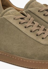 Zamszowe sneakersy w oliwkowym kolorze z teksturowaną cholewką, plecionymi beżowymi sznurówkami i gumową podeszwą z przeszytym brązowym wykończeniem.