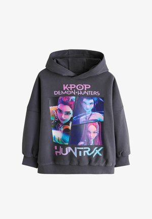 Czarna bluza z kapturem z kolorowymi animowanymi postaciami K-pop Demon Hunters oraz różowo-niebieskim napisem "K-POP DEMON HUNTERS HUNTRAX" z przodu.