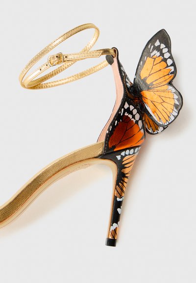 Guld højhælede sandaler med ankelrem, der har et design med orange og sort sommerfuglevinger og en 3D sommerfugldekoration på hælen.