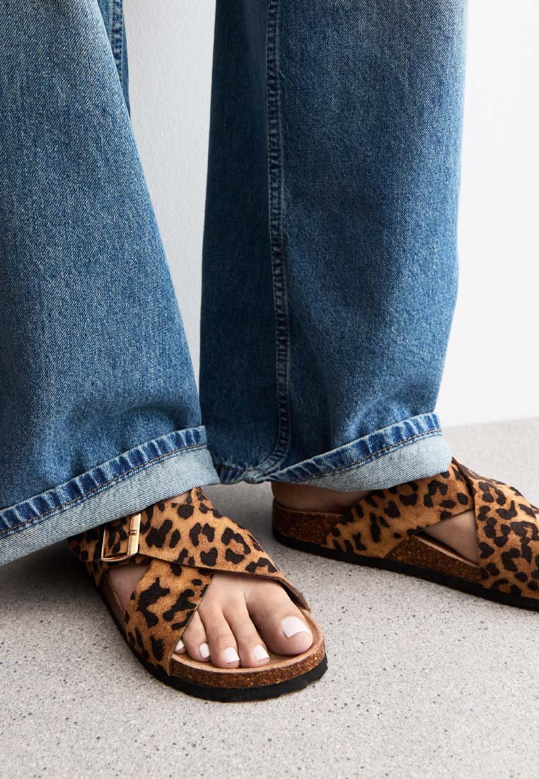 Leren sandaaltjes met luipaardprint, gemaakt van suede met een kurken zool, voorzien van een kruislings band ontwerp en een gesp accent, gedragen met wijde spijkerbroeken.