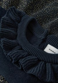 Tumesinine sviiter ribadega ümarate kaelustega, millel on rippuv aksessuaar. Pehme kudum, mille taustal on säravad kuldsed täpid.