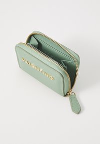 Portafoglio in pelle verde menta con finitura testurizzata, hardware dorato, chiusura con zip e dettaglio del logo. Presenta più slot per carte e scomparti.