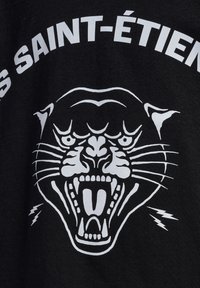 Svart t-shirt med en vit grafik av ett vrålande pantherhuvud, med texten "SAINT-ÉTIEN" ovanför och blixtar på sidorna.
